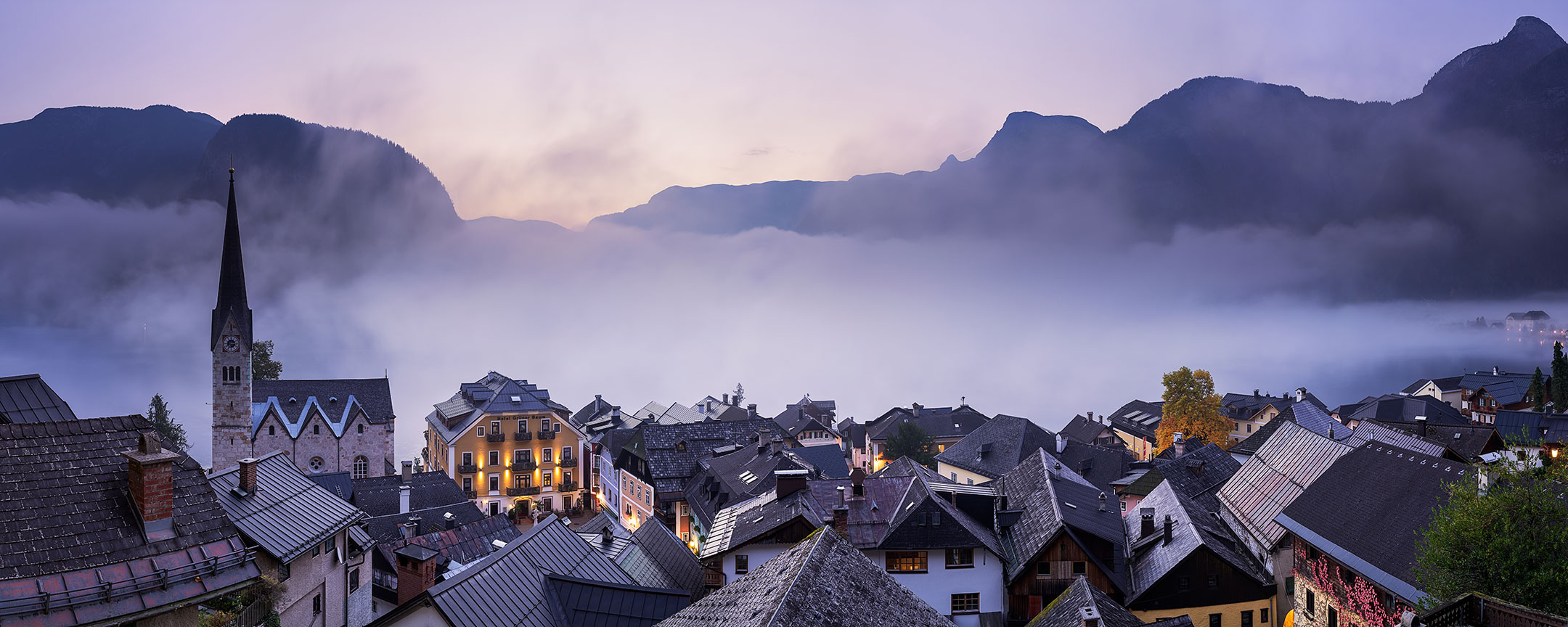 A foggy dawn rises over the roof tops of the quaint village of Hallstatt in Austria