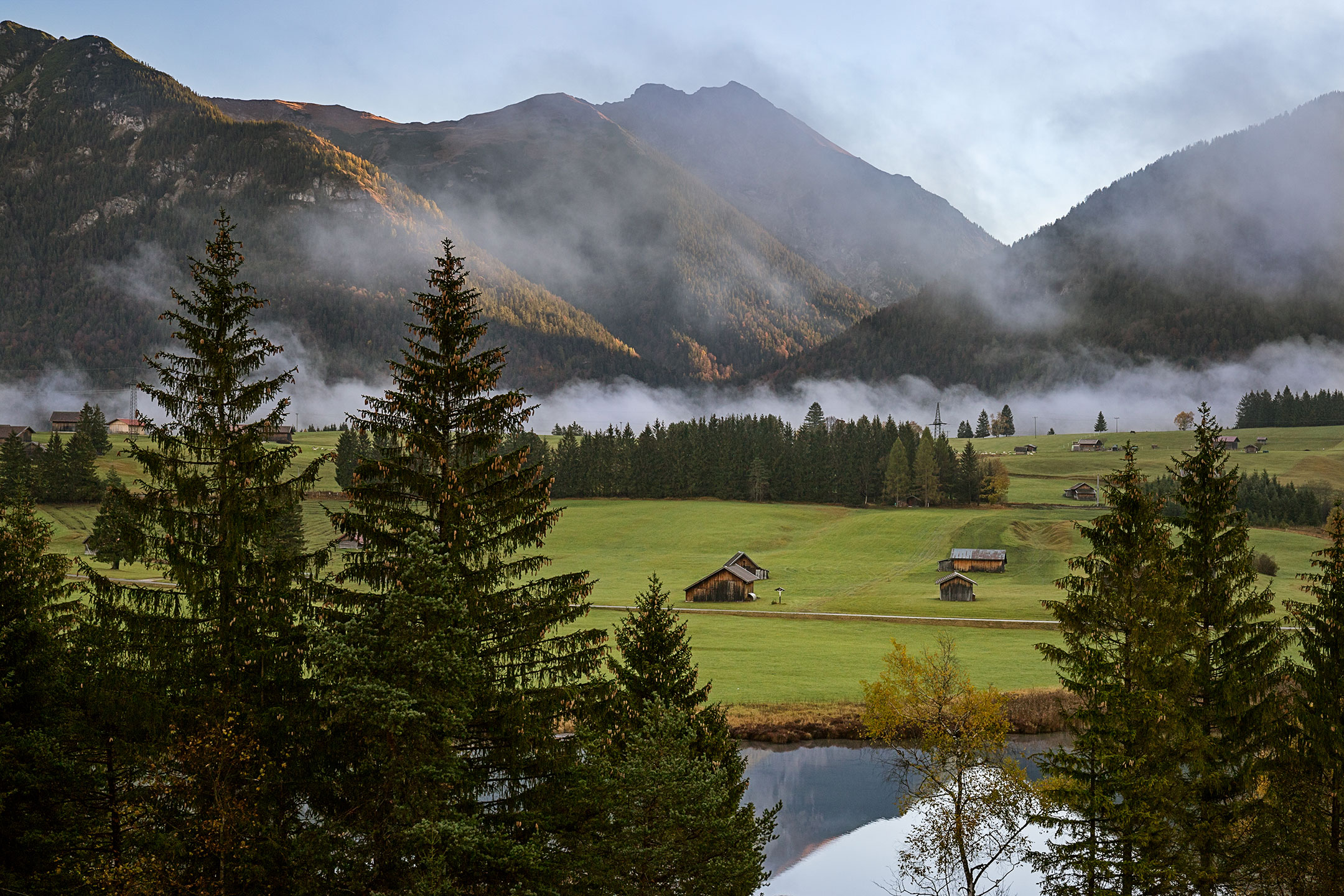 The last remnants of fog cling in the valley near Schmalsee, Mittenwald, Germany