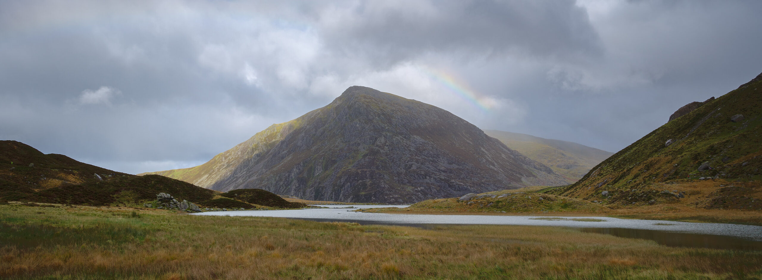 A rainbow peaks above the mountains in the Ogwen Valley, Snowdonia, Wales