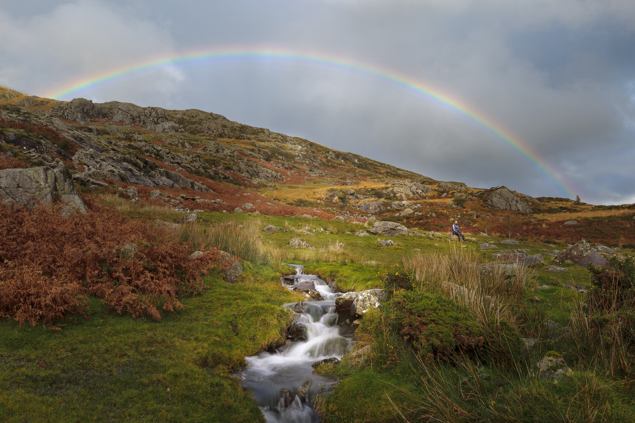 A rainbow arcs above a small stream in the Ogwen Valley, Snowdonia, Wales